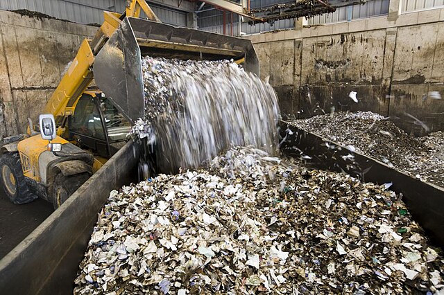 Picture showing shredded waste being emptied from a waste vehicle into a large container.