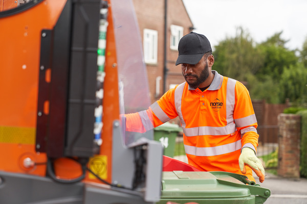 Picture showing a man loading a bin into the back of a bin lorry